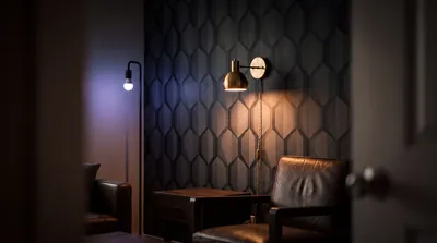 A brass plug-in wall sconce glowing against patterned peel-and-stick wallpaper
